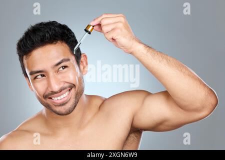 Cura della pelle, sorriso o uomo con siero in studio per il trattamento, olio di avocado o prodotto anti invecchiamento. Persona maschile, pipetta o pensiero per routine cutanea con Foto Stock