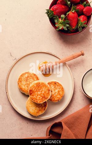 Frittelle di formaggio cottage con salsa bianca e fragole, su un tavolo beige, vista dall'alto, attenzione selettiva, nessuno Foto Stock