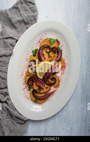 Polpo con patate e spezie, su un piatto leggero, vista dall'alto, niente persone, fatti in casa, primo piano Foto Stock