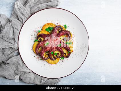 Polpo con patate e spezie, su un piatto leggero, vista dall'alto, niente persone, fatti in casa, primo piano Foto Stock