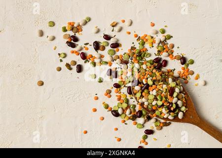 Cucchiaio di legno, con un assortimento di legumi, fagioli, piselli, vista dall'alto, su sfondo chiaro Foto Stock