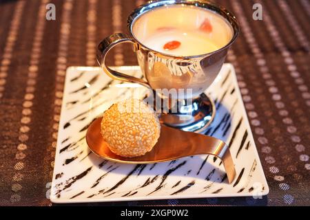 Palla di semi di sesamo appena fritta su un cucchiaio dorato e gelatina di mandorle in una tazza d'argento Foto Stock