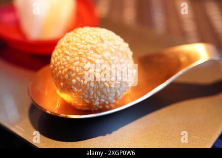 Palla di semi di sesamo appena fritta su un cucchiaio dorato Foto Stock
