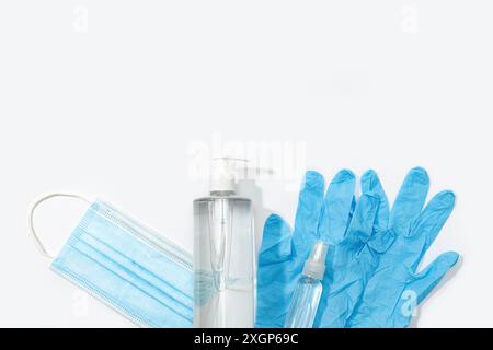 Concetto di protezione o prevenzione del coronavirus COVID-19. Maschera medica, guanti, disinfettante per le mani e spray disinfettante su sfondo bianco. Superiore Foto Stock