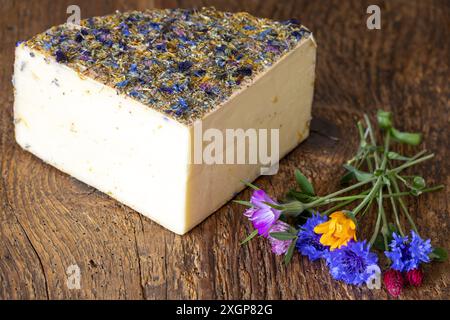 Formaggio di montagna con fiori su legno Foto Stock