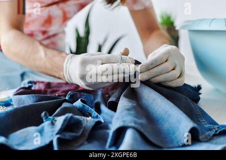 Un giovane designer cuce il tessuto denim nel suo atelier, concentrandosi sulla sostenibilità dando nuova vita ai vecchi vestiti. Foto Stock