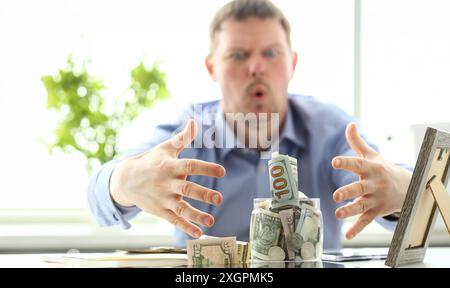 Mani maschio grabbing Big fat vaso pieno della valuta statunitense come gesto di avidità Foto Stock