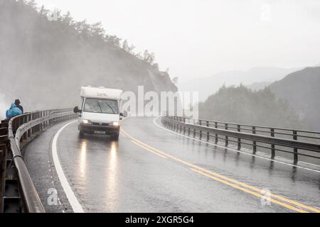 LANGFOSS, NORVEGIA - 9 AGOSTO 2016: Carovana bianca Fiat Ducato che guida in condizioni meteorologiche avverse sul ponte sotto la cascata Langfoss in Norvegia Foto Stock