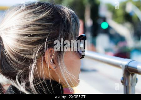 Bella donna con occhiali da sole da dietro che guarda alla sua destra Foto Stock