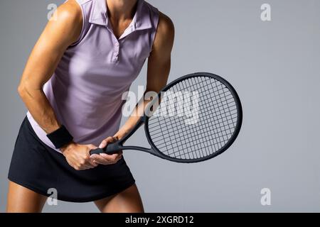 L'atleta in abito da tennis posa con una racchetta su sfondo bianco, con spazio copia. Cattura l'essenza dinamica di un tennista pronto per il gam Foto Stock