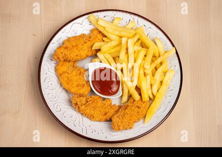 Vista dall'alto di un piatto di ali di pollo fritte croccanti con patatine fritte e un lato di ketchup su un tavolo di legno Foto Stock