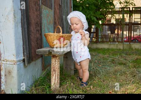 bambino in un cappello che regge una vecchia panchina con un cestino Foto Stock