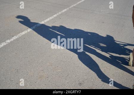 silhouette sulla strada di una donna che spinge un passeggino Foto Stock