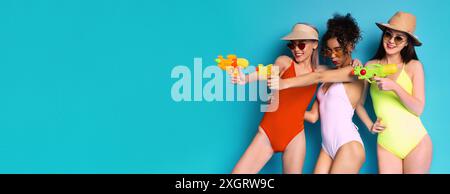 Tre giovani donne in costumi da bagno giocano con le pistole d'acqua Foto Stock