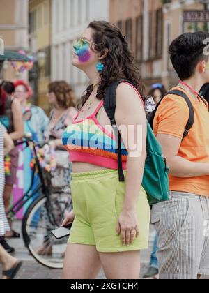 Cremona, Italia - 6 luglio 2024, Gay Pride lgbt Parade, giovane donna con un vivace trucco arcobaleno, cammina felicemente attraverso una strada vivace durante una vivace Foto Stock