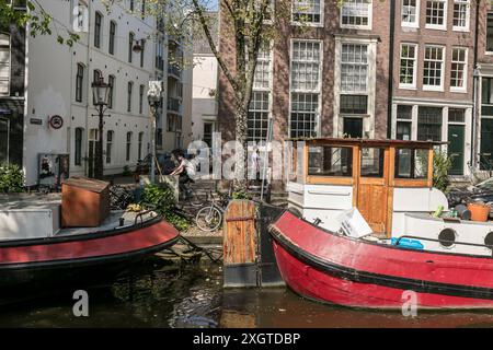 Case galleggianti ormeggiate sul lato di un canale in una giornata di sole ad Amsterdam, nei Paesi Bassi. Foto Stock