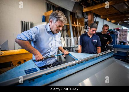 Bochum, Deutschland. 10 luglio 2024. Il ministro federale dell'economia e della protezione del clima Robert Habeck (Alleanza 90/Verdi) in un viaggio estivo attraverso la Germania. Qui a Bochum, 10 luglio 2024, visita un conciatetto con elementi del tetto solare. Fotografato per conto di BMWK/dpa/Alamy Live News Foto Stock