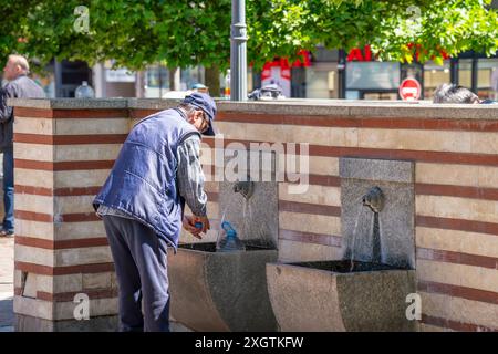 Sofia, Bulgaria. 25 maggio 2024. Un uomo riempie una bottiglia di plastica con acqua nella famosa sorgente di acqua minerale calda nel centro della città Foto Stock