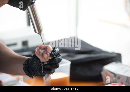 Cosce di pollo iniettando una marinata con una siringa Foto Stock