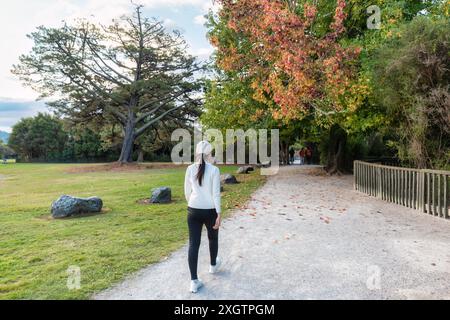 Bella donna asiatica che cammina e si fa esercizio nel parco autunnale di Cornwall Park, Auckland, nuova Zelanda Foto Stock