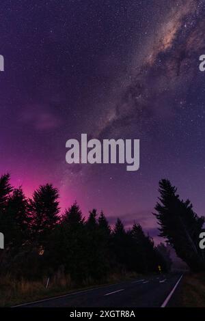 Splendida via Lattea e Aurora australis sopra la foresta sulla strada nella scena rurale dell'isola meridionale della nuova Zelanda Foto Stock