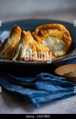 Uno shot ravvicinato del tradizionale Khinkali georgiano appena cucinato, servito in una ciotola blu intenso, che mette in risalto l'impasto testurizzato e il ripieno fumante Foto Stock
