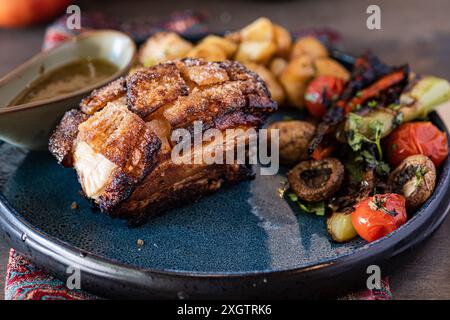 Succulento maiale al forno ricoperto da una ricca salsa al miele, accompagnato da un'insalata colorata di verdure alla griglia, tra cui pomodori e funghi, servita su Foto Stock