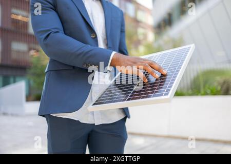 Immagine irriconoscibile ritagliata delle mani di un uomo d'affari nero che analizza un pannello solare Foto Stock