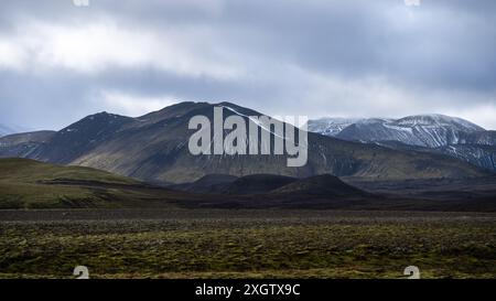Una vista mozzafiato dei paesaggi aspri e maestosi delle Highlands in Islanda, con torreggianti montagne sotto un suggestivo cielo coperto di nuvole. Foto Stock