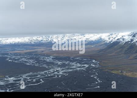 Fotografia aerea che cattura il paesaggio mozzafiato dell'Islanda, con ampie vedute delle montagne innevate e dei tortuosi fiumi glaciali che attraversano vasti fiumi Foto Stock