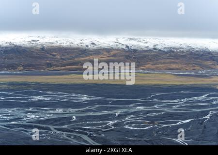 Questo scatto aereo cattura la straordinaria diversità dei paesaggi islandesi, caratterizzato da un terreno vulcanico scuro intrecciato con vivaci macchie di prato Foto Stock