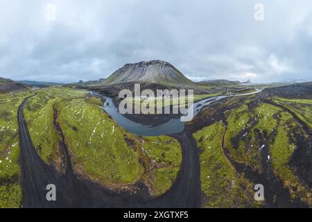 Vista panoramica delle strade tortuose attraverso i verdi altopiani dell'Islanda con maestose montagne. Foto Stock