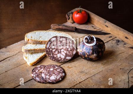 Salsicce affettate, forse salame, e fette di pane rustico presentate su una tavola di legno, catturando un ambiente tradizionale e appetitoso. Foto Stock