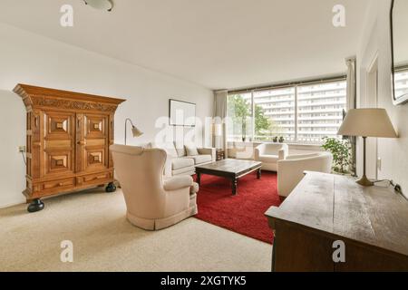 Un soggiorno ben arredato con un grande armadio in legno, comodi divani, tappeto rosso e ampie finestre che si affacciano sugli alti edifici, loc Foto Stock