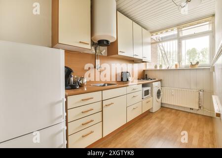 Questa invitante cucina, situata a Poststraat, nei Paesi Bassi, presenta un design compatto e funzionale con mobili in legno classici, elettrodomestici moderni e un Foto Stock