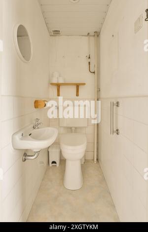 Bagno minimalista con piastrelle bianche, lavandino, WC e portasciugamani, situato a Poststraat, paesi Bassi ideale per il semplice e. Foto Stock