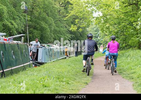 Vista posteriore di una famiglia che pedala lungo un percorso cittadino del Regno Unito, indossando caschi da ciclismo di sicurezza. Foto Stock