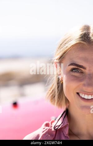 Una giovane donna caucasica sorride brillantemente durante un viaggio in auto, con spazio per le copie. La sua espressione gioiosa illumina l'ambiente soleggiato all'aperto. Foto Stock