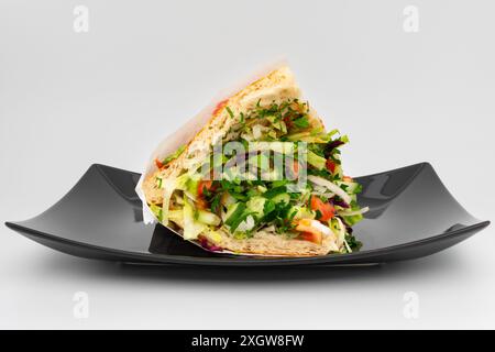 Kebab vegetariano döner verdure su un piatto. Il panino donatore si trova in un ambiente studio. Ingredienti freschi come cavolo, pomodori e cetrioli Foto Stock