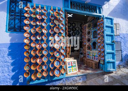 Chefchaouen, Marocco - 25 marzo 2024: Un negozio di artigianato che espone piatti e specchi di ceramica colorata nelle strade dipinte di blu. Foto Stock