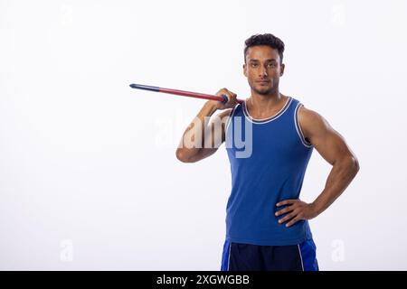 Il giovane uomo birazziale posa con sicurezza con un giavellotto su sfondo bianco, con spazio di copia. Il suo abbigliamento sportivo suggerisce la passione per lo sport e i phy Foto Stock