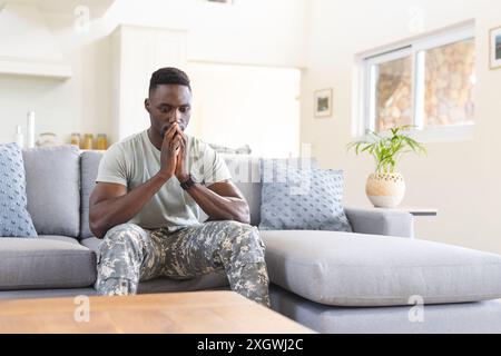 Un soldato afroamericano in difficoltà seduto sul divano a casa a pensare, copiare spazio. Depressione, ptsd, servizio militare, esercito, ritorno, casa, mentale h Foto Stock