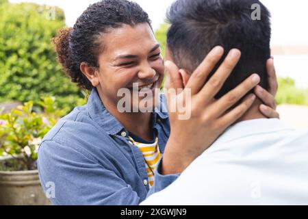 Il giovane uomo birazziale condivide un momento tenero con un uomo del Medio Oriente all'aperto. La loro calda interazione evidenzia un forte legame di amicizia o amore. Foto Stock