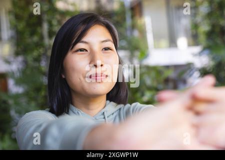Felice donna asiatica che pratica yoga e si allunga in giardino a casa. Fitness, esercizio fisico, vita domestica, attività e stile di vita, inalterati. Foto Stock