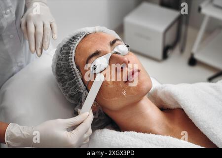 Una donna applica il gel al viso prima di una procedura laser. Foto Stock