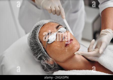 Una donna applica il gel al viso prima di una procedura laser. Foto Stock