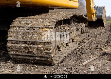 Primo piano del binario sull'escavatore nel cantiere stradale. Concetto di manutenzione, assistenza e riparazione di infrastrutture e attrezzature di movimento terra. Foto Stock
