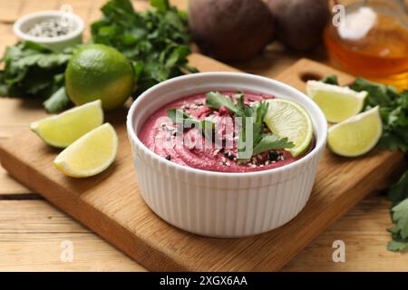 Gustoso hummus di barbabietola con lime e prezzemolo nel recipiente su un tavolo di legno Foto Stock