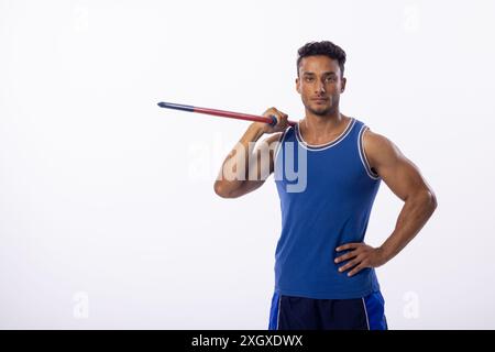 Il giovane uomo birazziale posa con sicurezza con un giavellotto su sfondo bianco, con spazio di copia. Il suo abbigliamento sportivo suggerisce la passione per lo sport e i phy Foto Stock