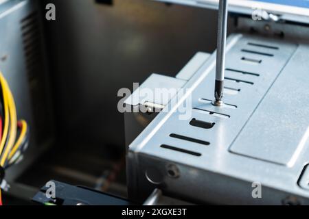 Tecnico PC che regola la vite sul coperchio di un armadio. Lavorare in un armadietto per computer. Foto Stock